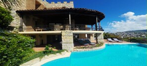 Un edificio de piedra de dos pisos con piscina, mobiliario exterior y vistas al paisaje.