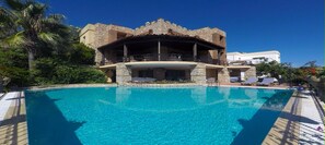 Een buitenzwembad, parasols bij het zwembad en ligstoelen