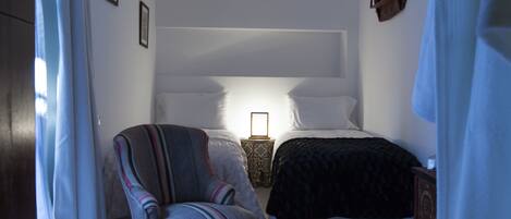 A bedroom with a bed, a chair, a nightstand, and a lamp.