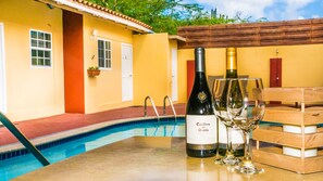 A poolside area with a table, two wine bottles, and glasses.