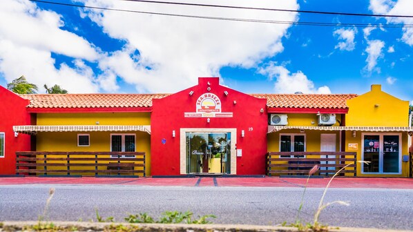 A colorful building with a red, yellow, and orange facade, featuring a prominent sign for Sea Breeze Apartments.