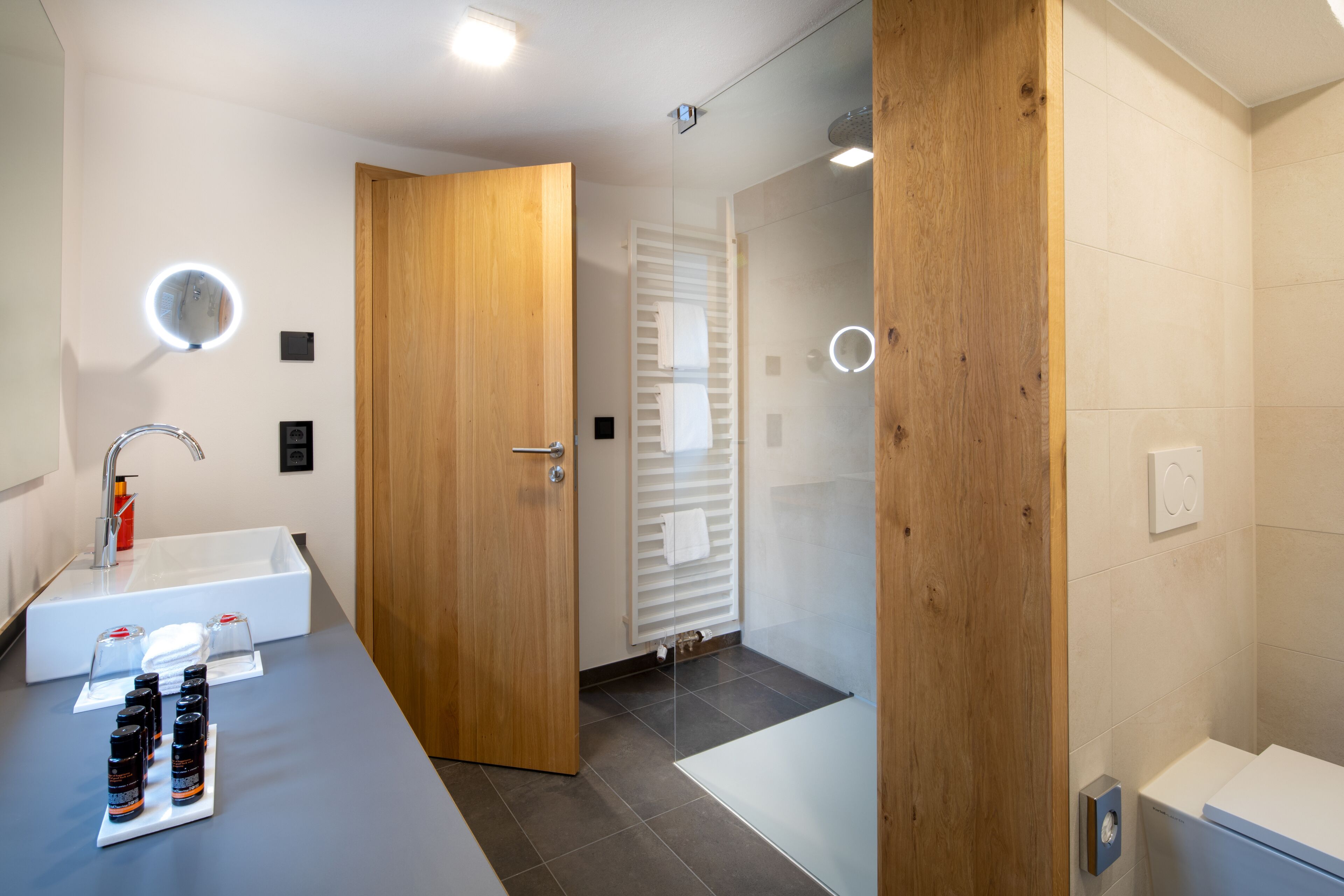Un baño moderno con un lavamanos grande, detalles de madera y una cabina de ducha de vidrio.