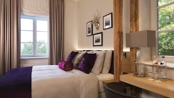 A hotel room with a bed, a desk, a chair, a window with curtains, and wall-mounted pictures.