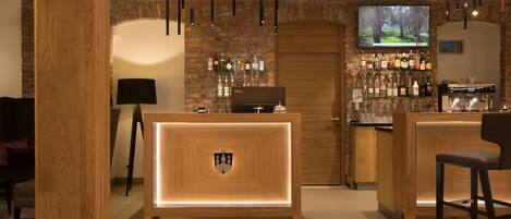 Zona de bar con muebles de madera, un televisor y una variedad de botellas.