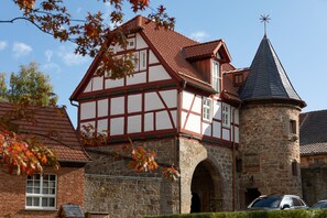 A traditional half-timbered house with a stone tower and a steeply pitched roof. - Hotel Brunnenhaus Schloss Landau (Bad Arolsen)