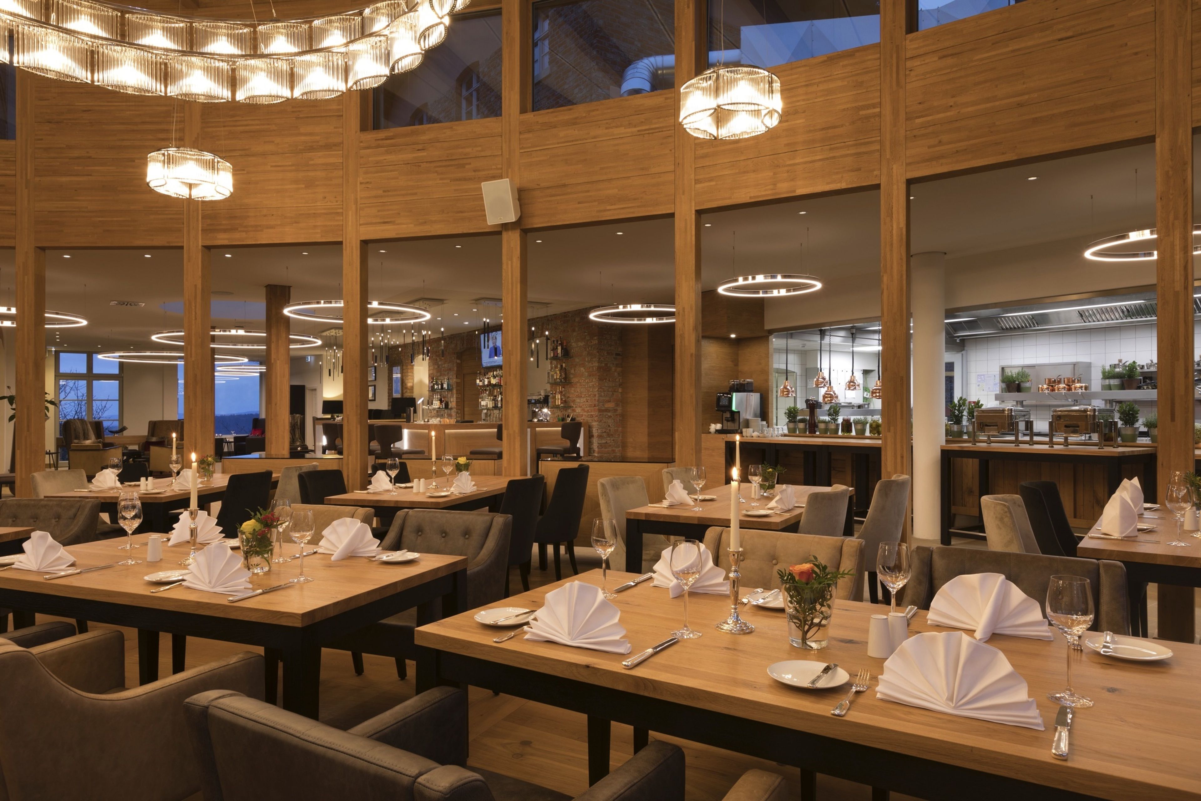 Un restaurant avec des tables et des chaises en bois, des bougies et un bar situé au fond de la salle.