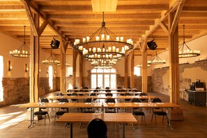 Ein Konferenzraum mit mehreren Tischen, Stühlen und einer großen Chandelüster.