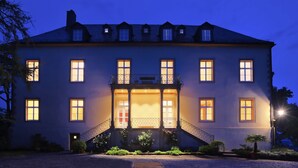A large, two-story building with multiple windows, a central entrance with steps, and a balcony with a railing. - Hotel Brunnenhaus Schloss Landau (Bad Arolsen)
