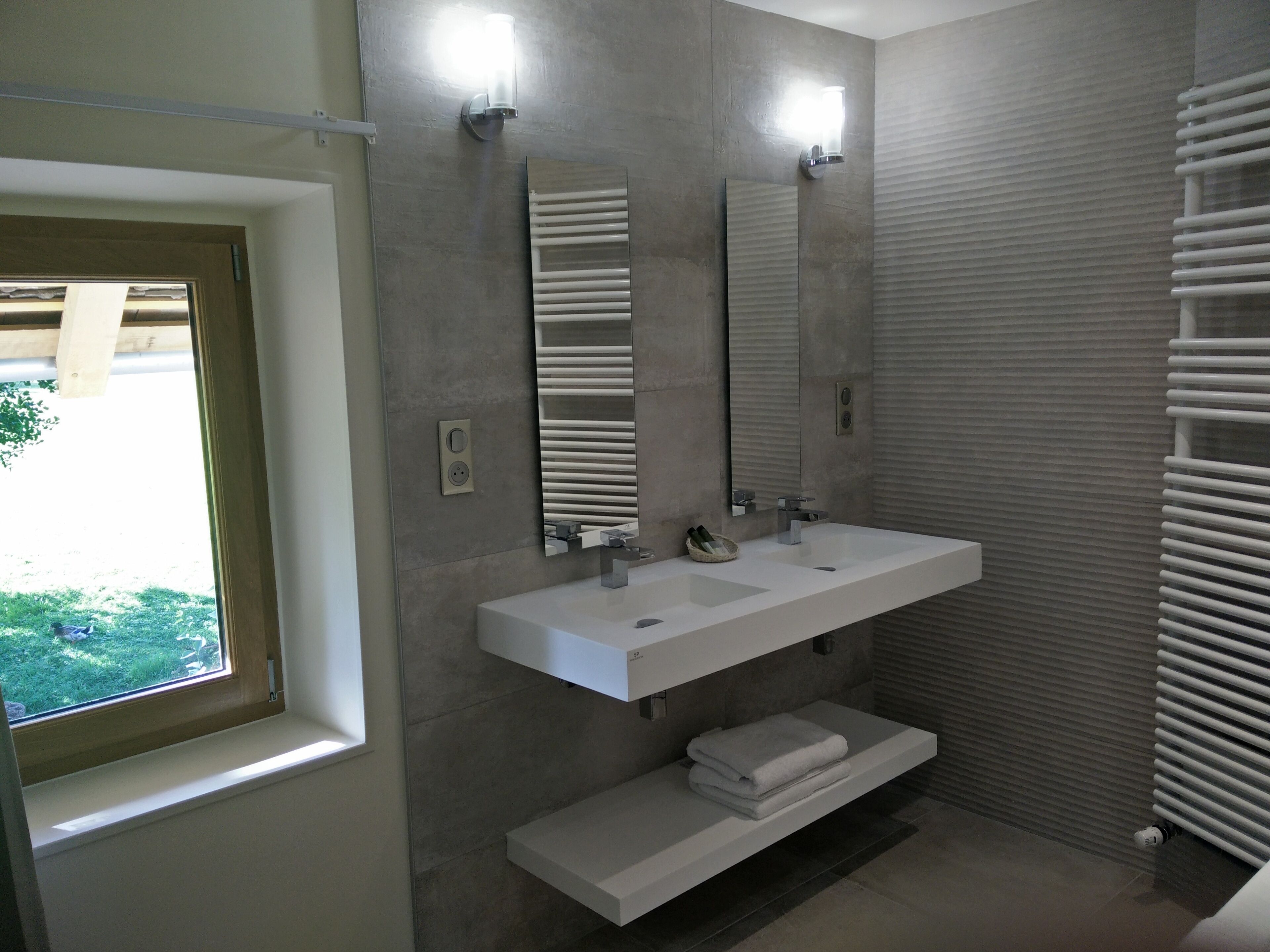 Een moderne badkamer met twee wasbakken, een grote spiegel en een handdoekhouder.
