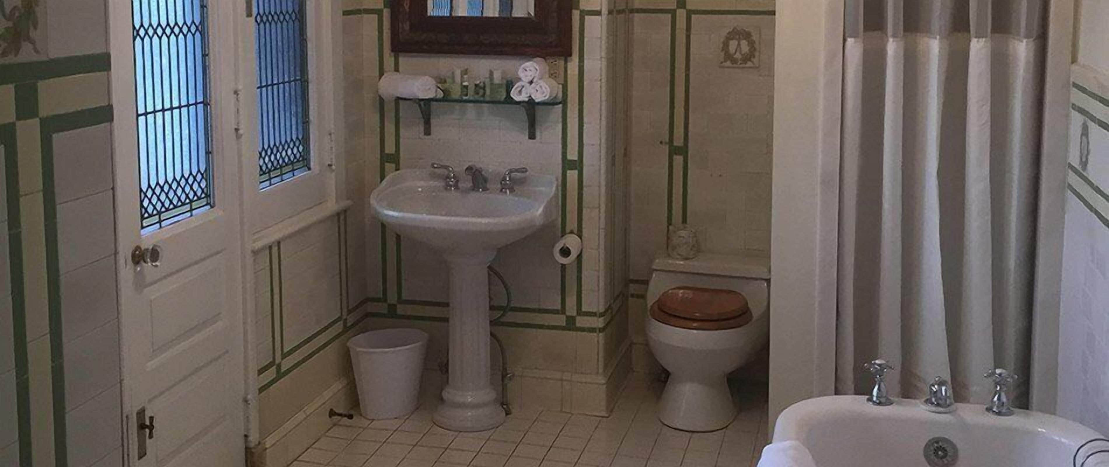 A small bathroom with a pedestal sink, toilet, and bathtub.