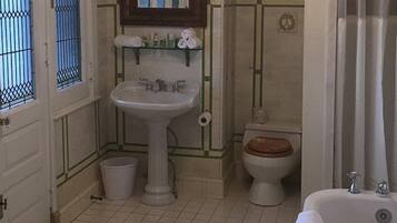 A small bathroom with a pedestal sink, toilet, and bathtub.