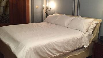 Una cama bien hecha con ropa blanca en una habitación con muebles de madera y apliques.