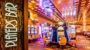 L’intérieur d’un casino, avec ses machines à sous, ses enseignes au néon et une moquette aux couleurs vives.
