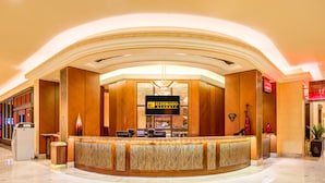 Un espace d’accueil doté d’un comptoir en bois aux lignes courbes, d’une enseigne indiquant « Eldorado Resorts » et d’un lustre moderne.