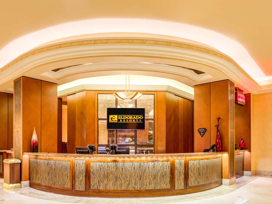 A reception area with a curved wooden counter, a sign for Eldorado Resorts, and a modern chandelier.