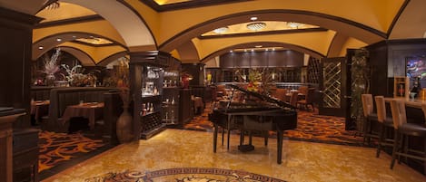 Un vaste hall d’entrée agrémenté d’un magnifique piano à queue, d’un tapis somptueux et d’un bar avec des étagères remplies de bouteilles.
