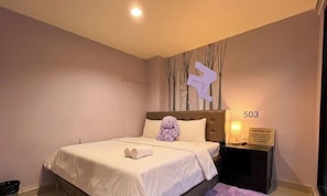 Une chambre d’hôtel avec un lit, un jouet en peluche, une table de chevet et une pancarte indiquant le numéro de chambre : 503.