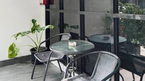 A modern interior with a sign reading 'RABBIT ROOM,' featuring glass tables and wicker chairs, with a view through large windows.