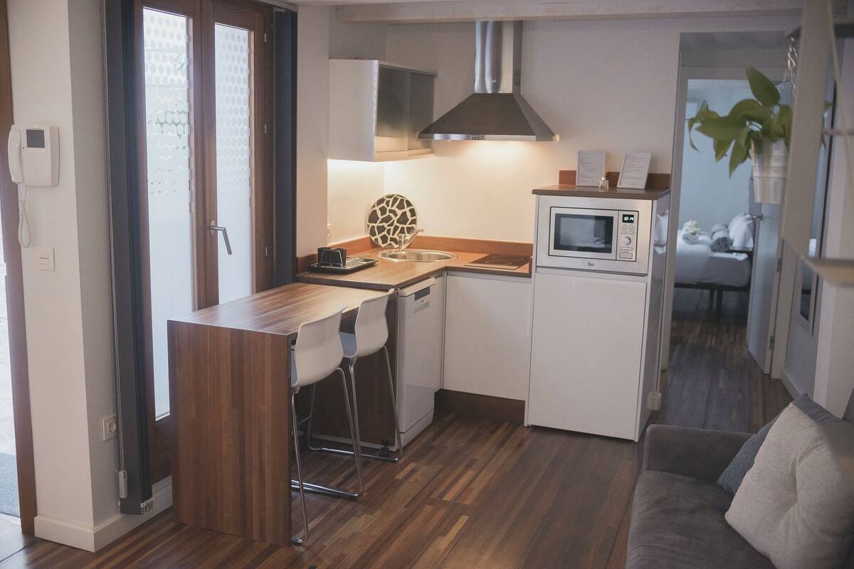 Eine kleine Küche mit Holzarbeitsplatte, einer eingebauten Mikrowelle und einem kleinen Kühlschrank.