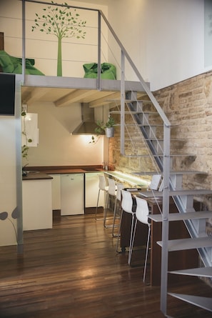 A modern kitchen with a wooden countertop, a built-in dishwasher, and a staircase leading to an upper level. - Lofts Trigo 13 (Córdoba)