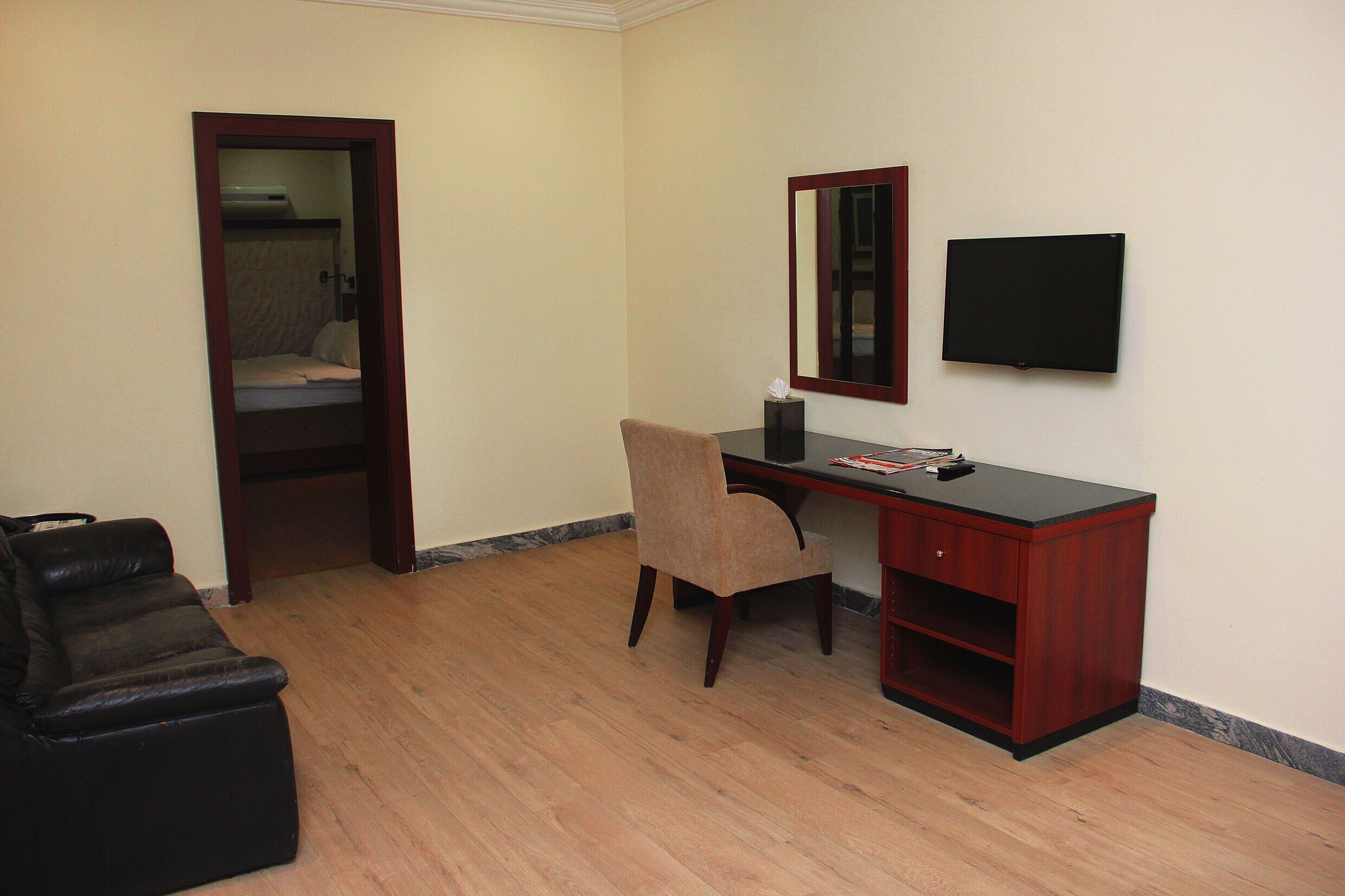 A room with a desk, chair, and a television.
