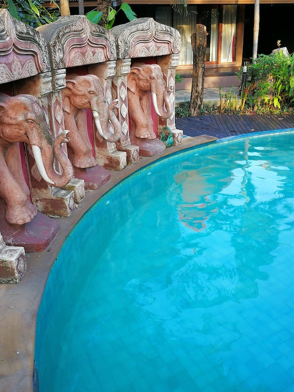 A swimming pool with decorative elephant statues lining the edge.