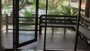 An open sliding door leading to an outdoor area with a wooden deck, benches, and greenery. - The Imperial Home Hotel (Bangkok)