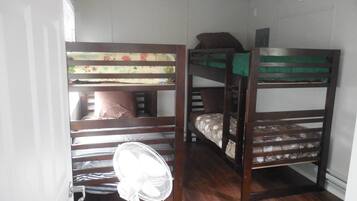 Een slaapkamer met stapelbed, ventilator en raam.