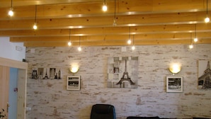 A cozy room with a wooden ceiling, a black leather sofa, a white armchair, and a small table. - Hostal Platja (Cambrils)