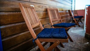 Wooden chairs with blue cushions against a wooden wall.