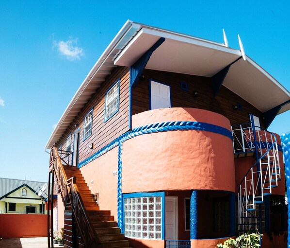 A two-story building with a wooden facade, a blue trim, and a white door. - Paradise Home Apartments (Canaan)