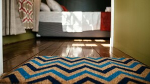 A wooden floor leading to a bed with a patterned bedspread and pillows.