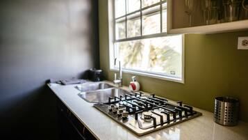 A kitchen with a gas stove, a sink, and a window with a view of trees.