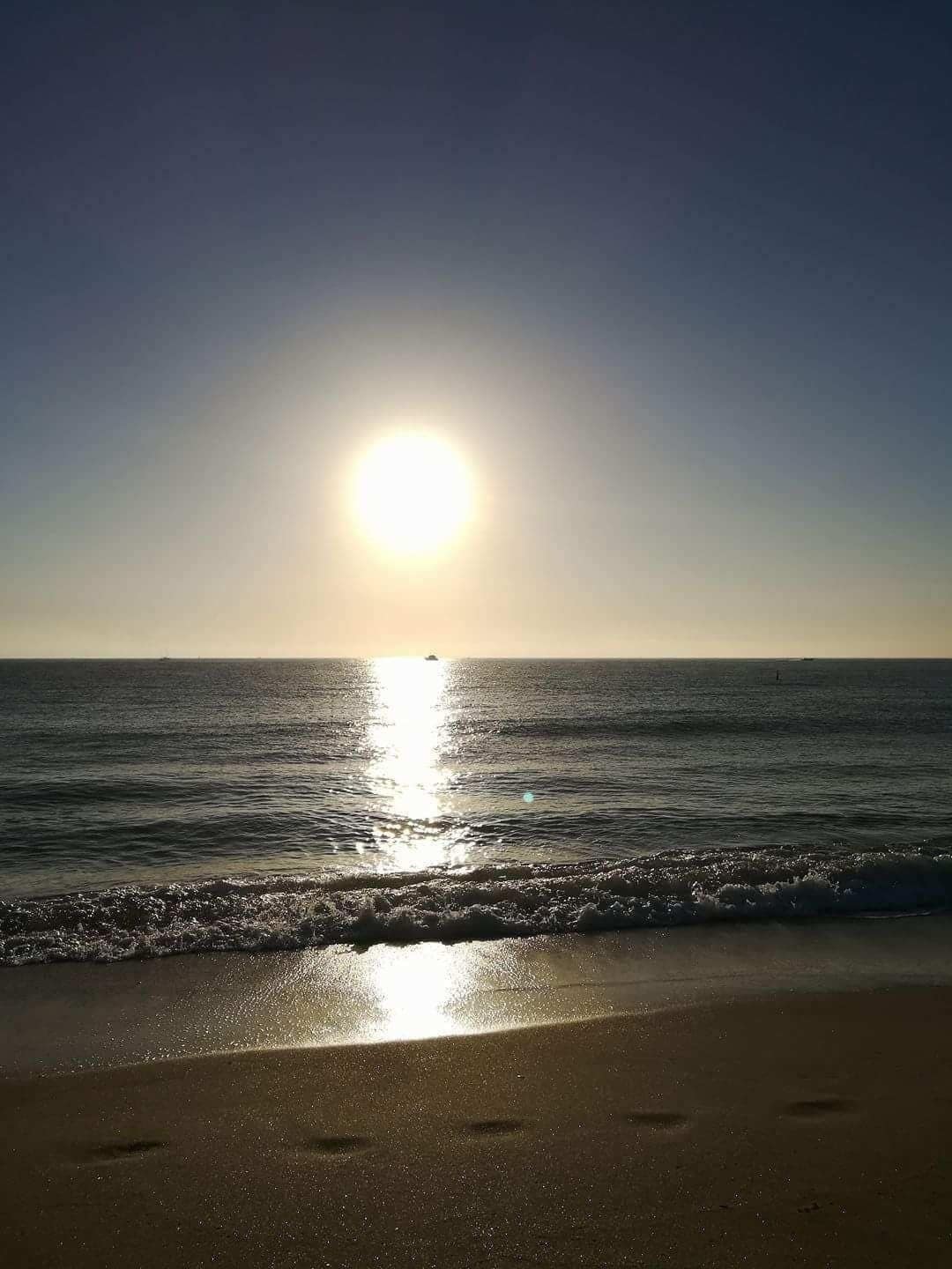 A beach with the sun reflecting on the water.