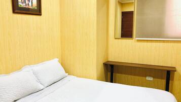 Une chambre d’hôtel avec un lit, une table de chevet, un miroir et un tableau accroché au mur.