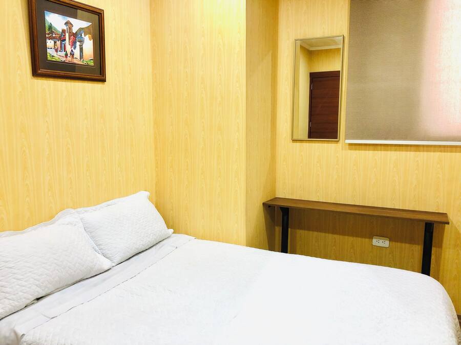Une chambre d’hôtel avec un lit, une table de chevet, un miroir et un tableau accroché au mur.