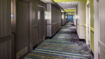 Ein Hotelgang mit Streifenmuster-Teppich, Türen an beiden Seiten und einer grünen Decke.