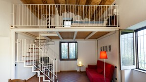 A loft-style room with a wooden staircase, a red sofa, and a window with a view of trees. - Farm holidays with pool in Sicily, among the Nebrodi's park and close to the sea (Rocca di Capri Leone)