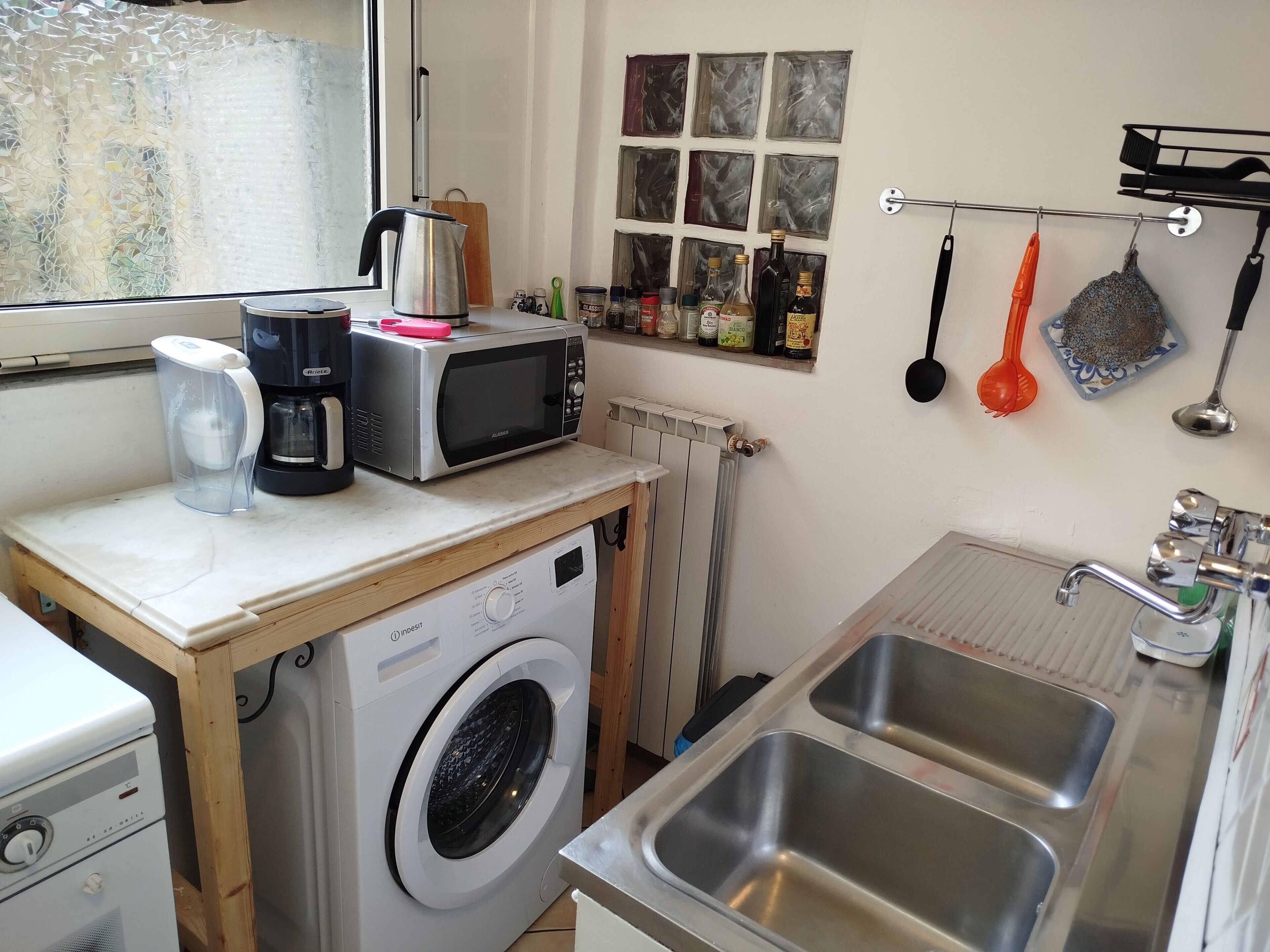 A compact kitchen with a washing machine, a microwave, a coffee maker, and a sink.