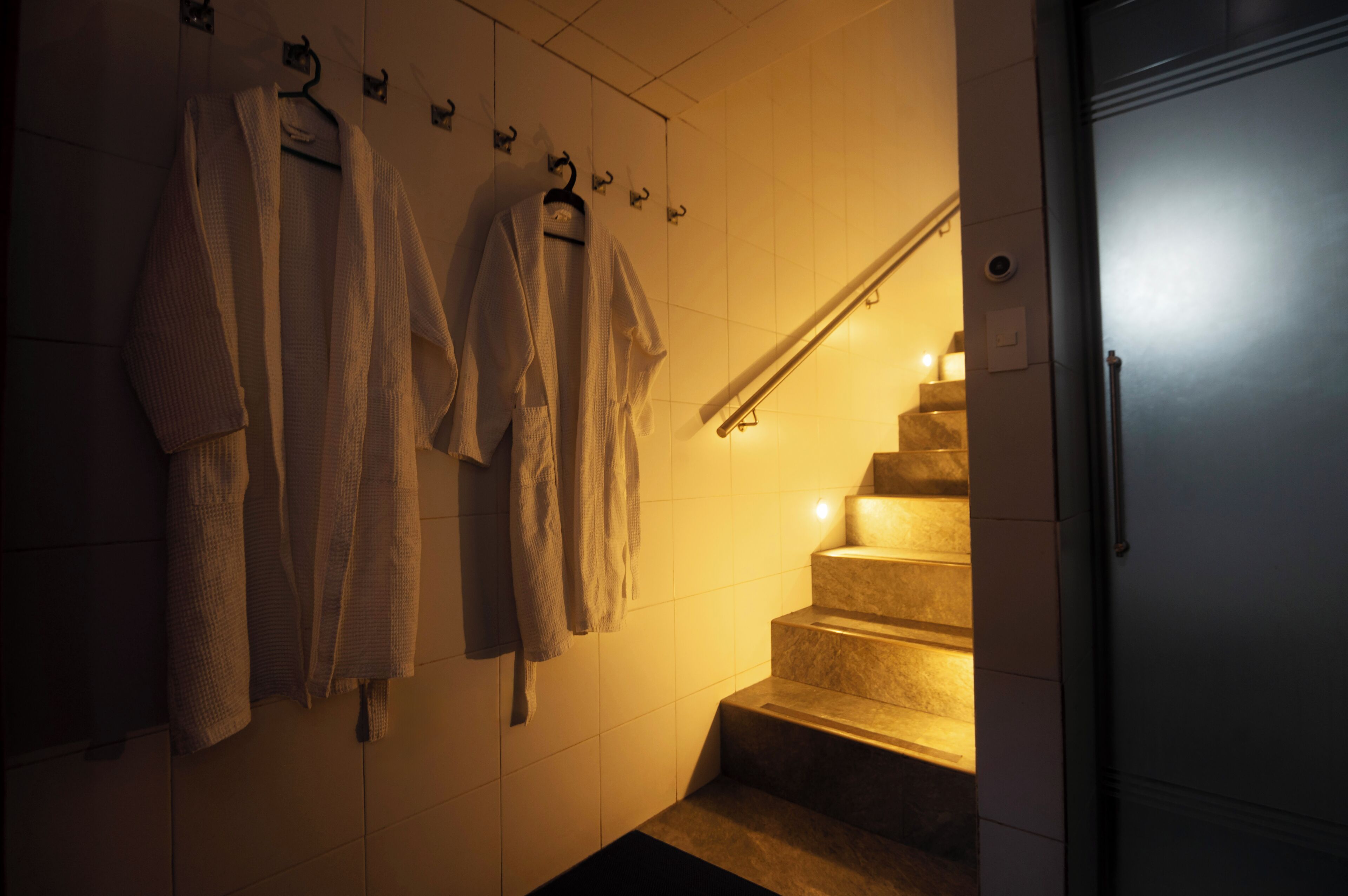 Une salle de bain avec un mur carrelé, un escalier et une main courante.
