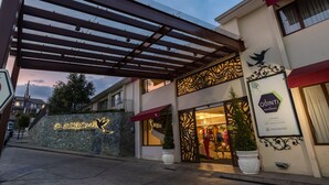 A hotel entrance with a stone wall, a red awning, and a sign for 'Quindeloma Art Hotel'. - Quindeloma Art Hotel And Gallery (Riobamba)