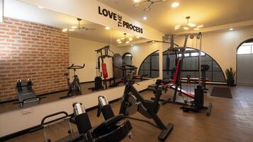 Un gimnasio con equipo de ejercicio, un espejo grande y una frase motivacional en la pared.