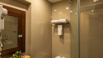 A modern bathroom with a glass shower enclosure, a white toilet, and a granite countertop with a sink.