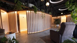 A modern interior with a curved wooden partition, a grey sofa, and potted plants. - Quindeloma Art Hotel And Gallery (Riobamba)
