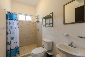 A bathroom with a shower, toilet, sink, and a towel rack.