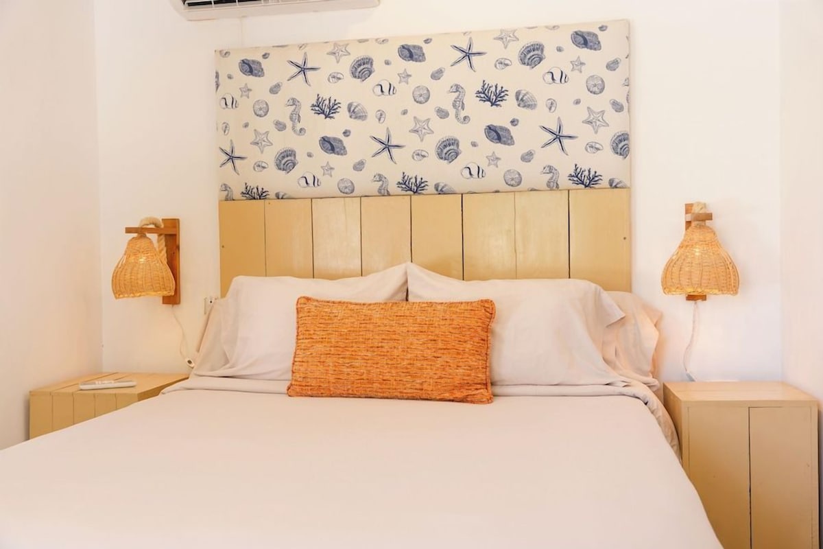 A bed with a headboard, two bedside lamps, and a wall with a nautical-themed pattern.