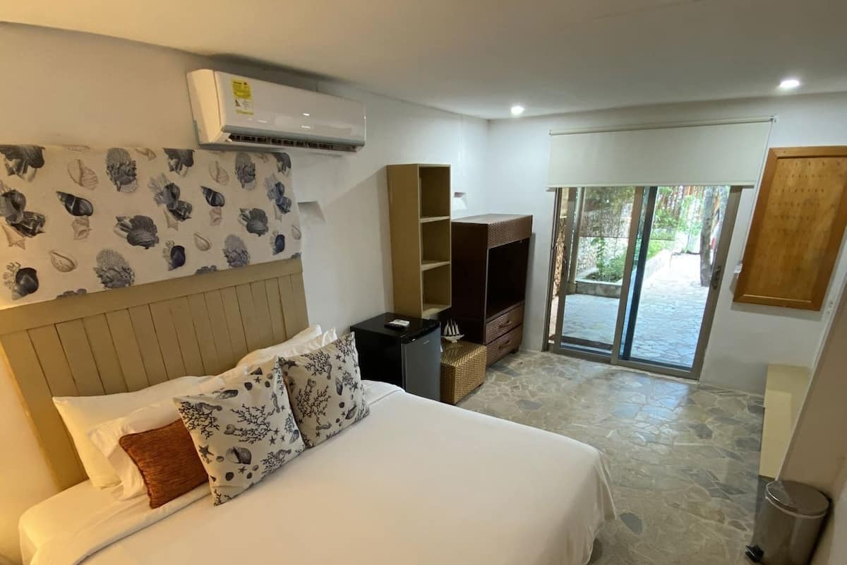 Un dormitorio con una cama grande, un armario, un televisor y vistas a través de un ventanal.