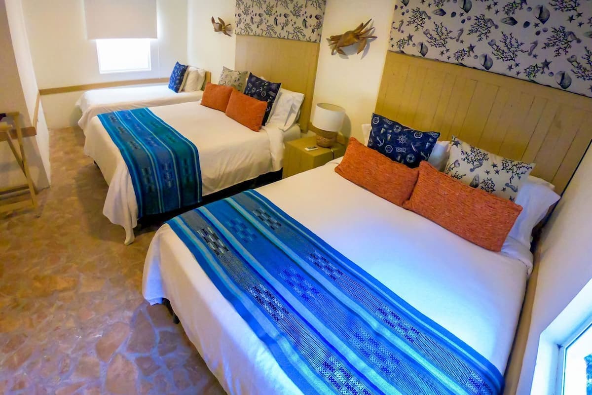 Una habitación de hotel con dos camas, una mesita de noche, una lámpara y una ventana con persianas.