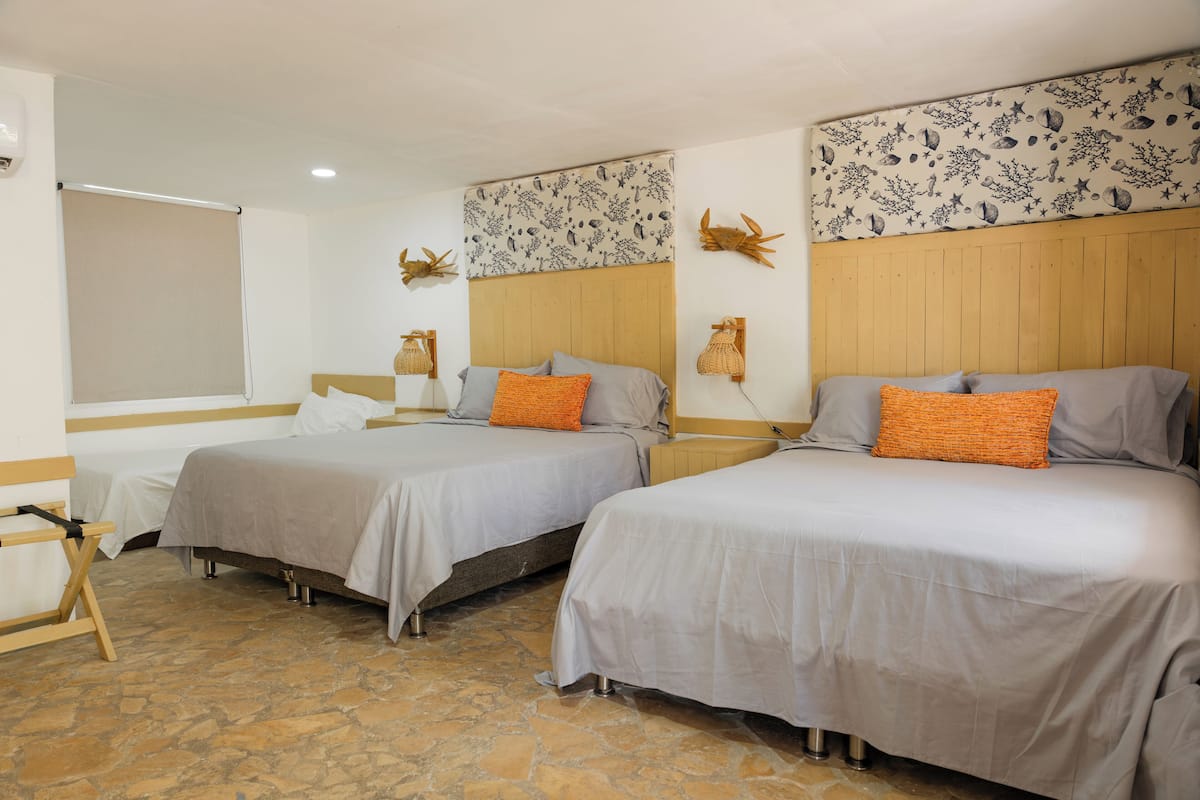 Habitación de hotel con dos camas, suelo de piedra, cabecero de madera y una pared con diseño celestial.