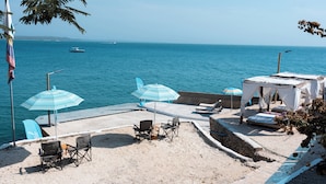 A beachside patio with chairs, umbrellas, and a small tented area overlooking the sea. - Hotel Isla Real (Cartagena)